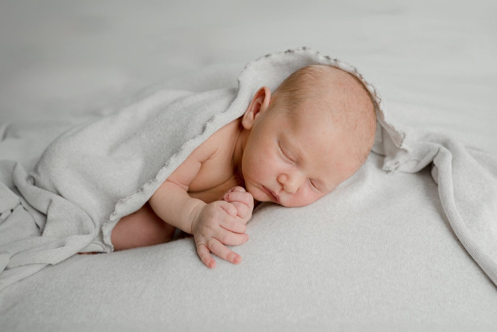 nouveau-né endormi sur un tissu gris clair
