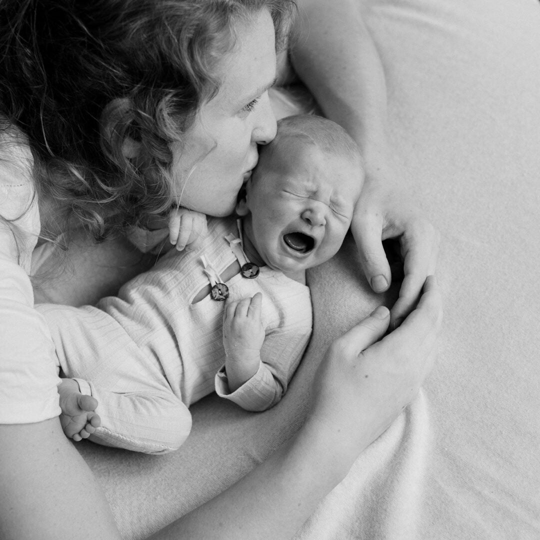 un nouveau-né pleurant consolé dans lèseras de sa maman