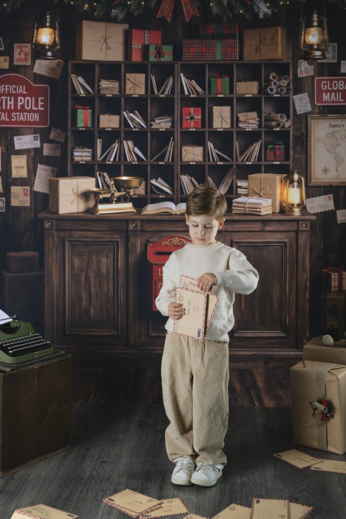 Enfant glissant sa lettre dans une enveloppe adressée au Père Noël, mini séance photo de Noël à Haguenau