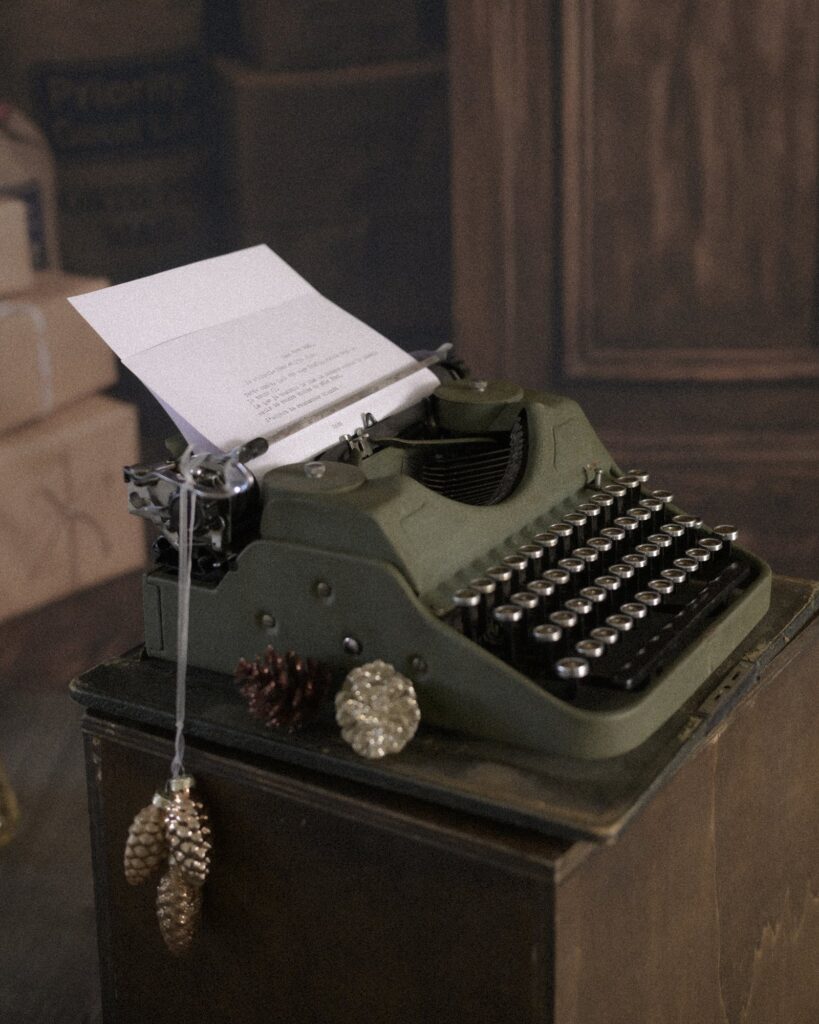 Machine à écrire vintage verte et pommes de pin dorées dans le décor de Noël de la mini séance photo