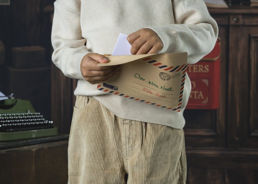 Mains d'enfant sortant une lettre d'une enveloppe « Cher père Noël, Pôle Nord », photo de Noël pour enfant